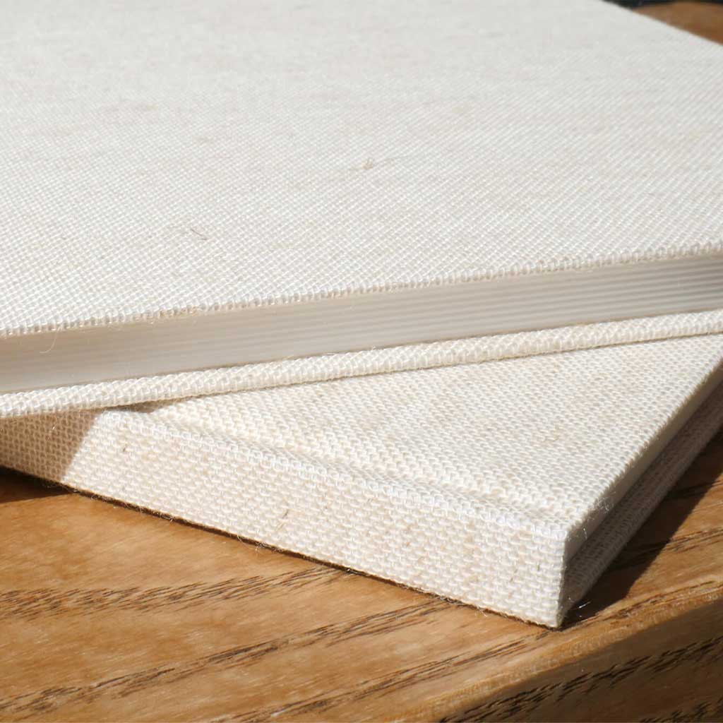 Two beige notebooks in sun on wooden surface