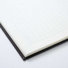 Close-up of gridded notebook with black binding on a light gray background