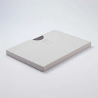Grey notebook in light grey kraft packaging on light surface