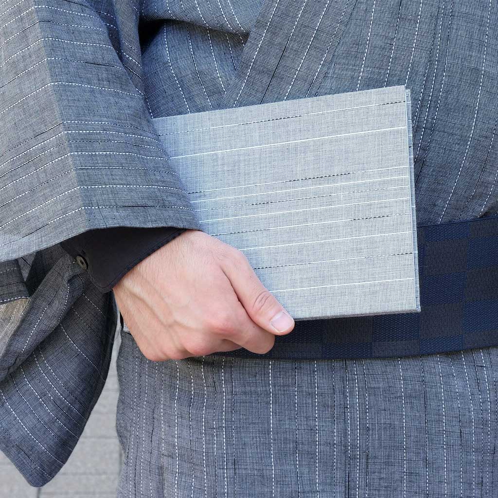 Person holding a gray fabric notebook against a blue pinstripe kimono background