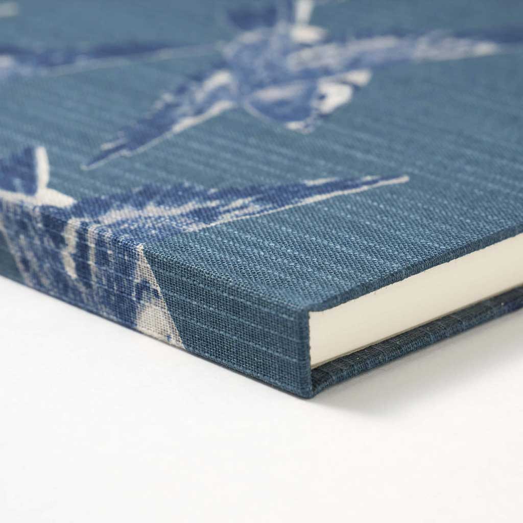 Notebook with a blue cover featuring white bird pattern on a white background