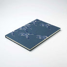 Notebook with a blue cover featuring white bird pattern on a white background
