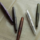 Five frosted rollerball pens laying on graph paper