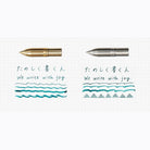 Side by side comparison of Kakimori brass and stainless steel pen nibs with writing examples on gridded paper background