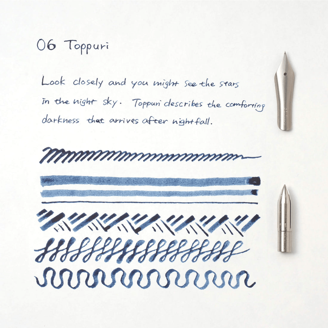 Ink pen nibs with blue sample writing on a white background