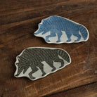 Two hand-painted ceramic wolf-shaped dishes on a rustic wooden table. 