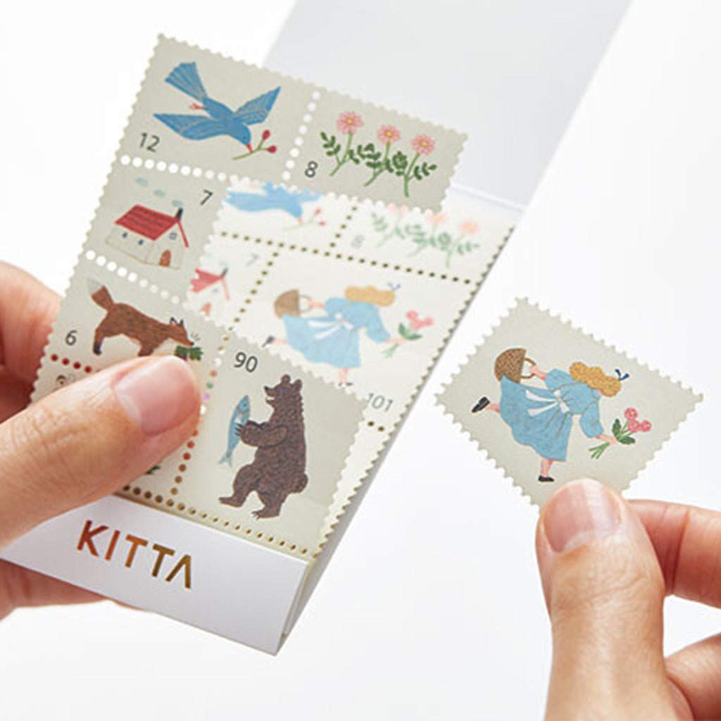 Hand holding stamp-style washi sticker with colorful illustration of girl running next to set of stickers in holder against white background