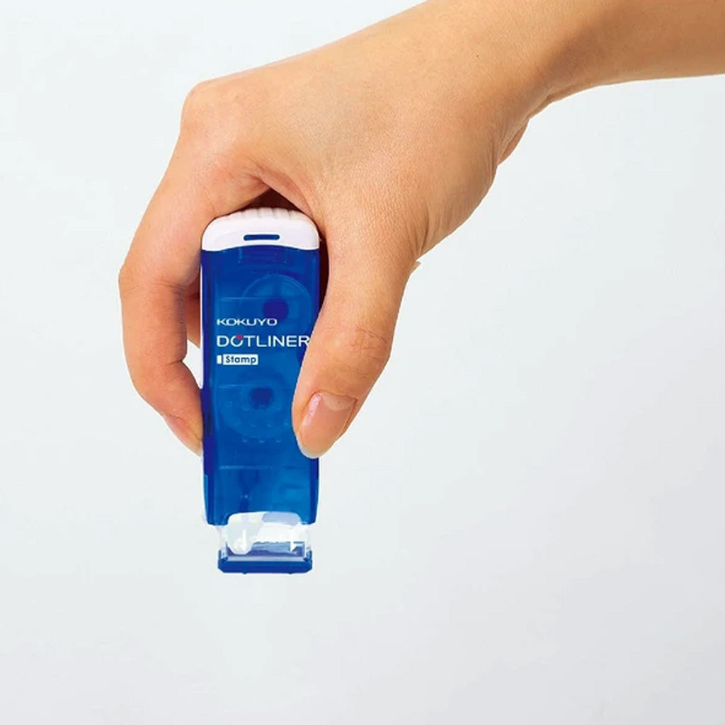 Hand holding a Blue Kokuyo Dotliner Adhesive Roller Stamp with white logo on white background