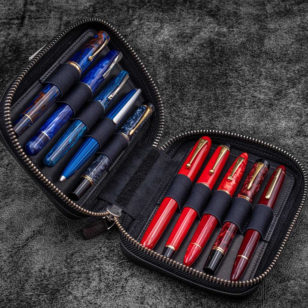 Black leather zippered pen pouch with ten colorful pens on a dark surface