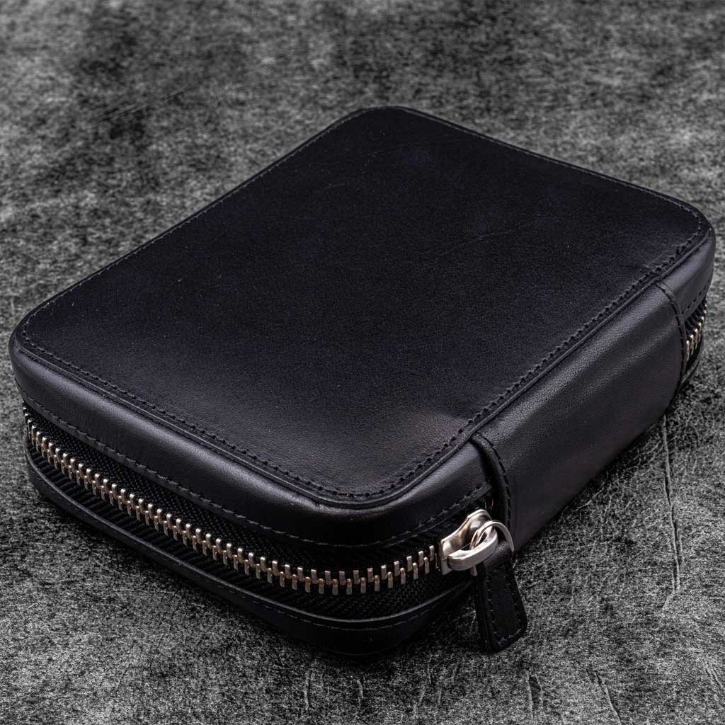 Black leather zippered pen pouch on a dark surface