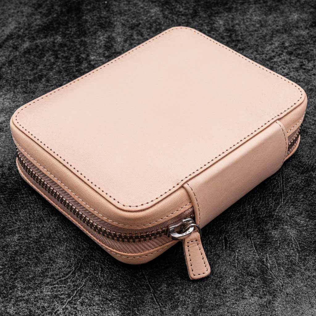 Natural undyed leather zippered pen pouch on a dark surface