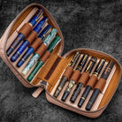 Natural undyed leather zippered pen pouch with ten pens on a dark surface