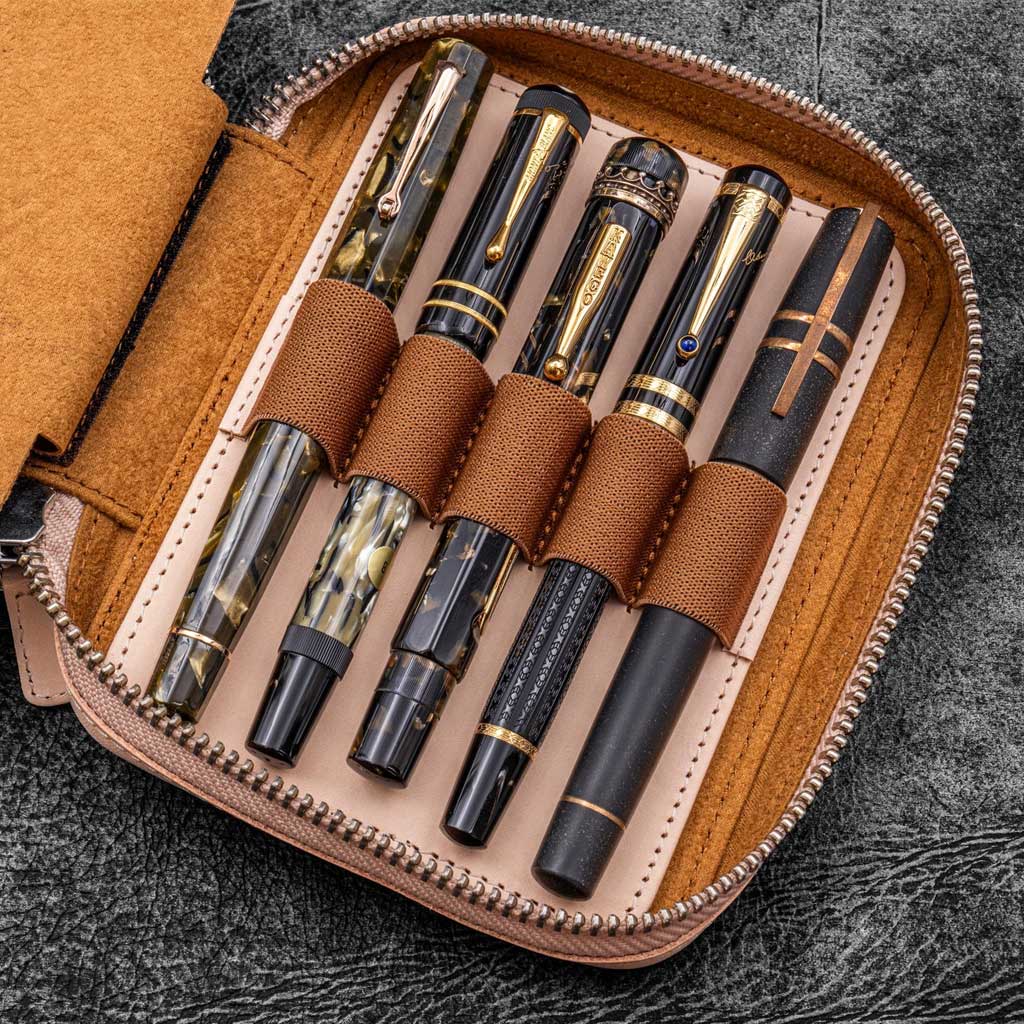 Natural undyed leather zippered pen pouch with five pens on a dark surface