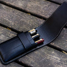 Three pens in Black leather pen case on wooden background