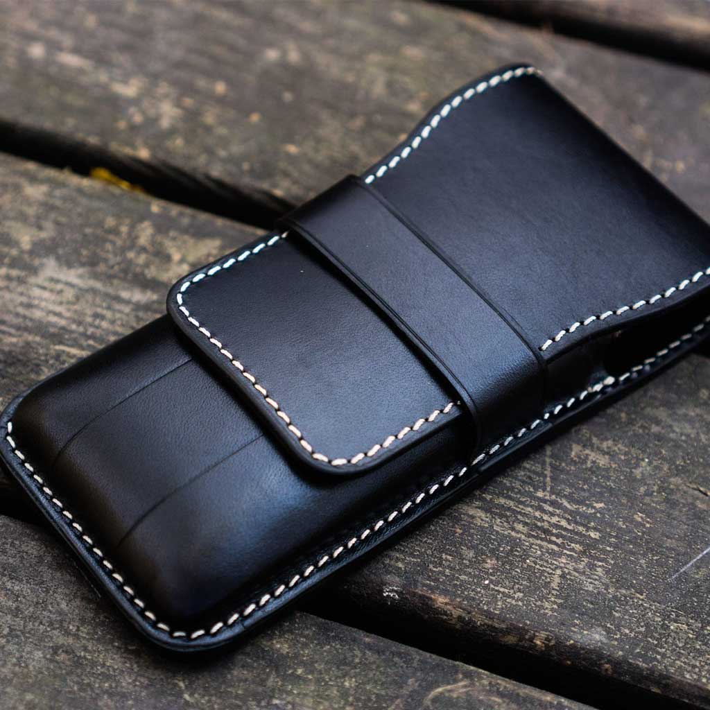 Black leather pen case on wooden surface