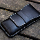 Black leather pen case on wooden surface