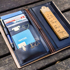 Black leather Traveler's Notebook wallet insert with clips and papers on wooden surface
