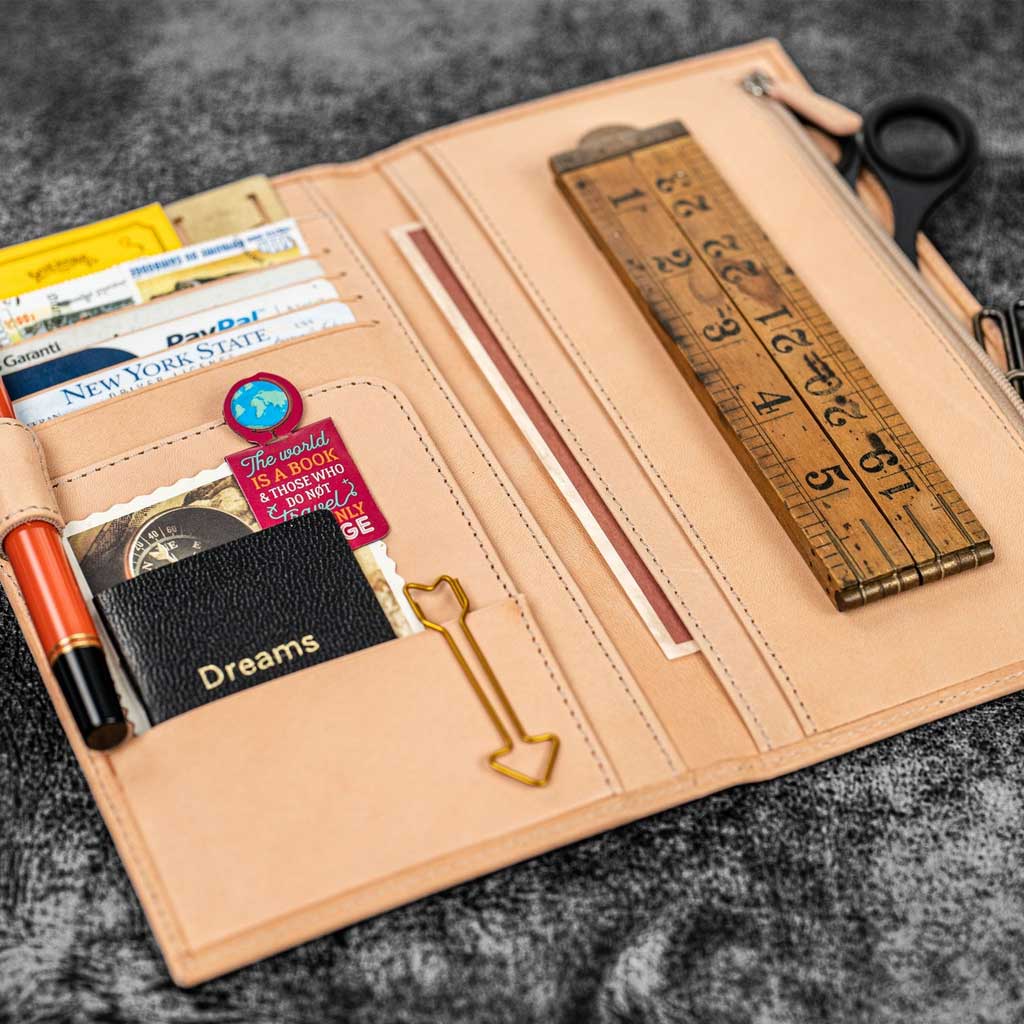 Natural undyed leather Traveler's Notebook wallet insert with clips and papers on wooden surface
