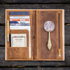 Brown leather Traveler's Notebook wallet insert with clips and papers on wooden surface