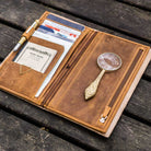 Brown leather Traveler's Notebook wallet insert with clips and papers on wooden surface
