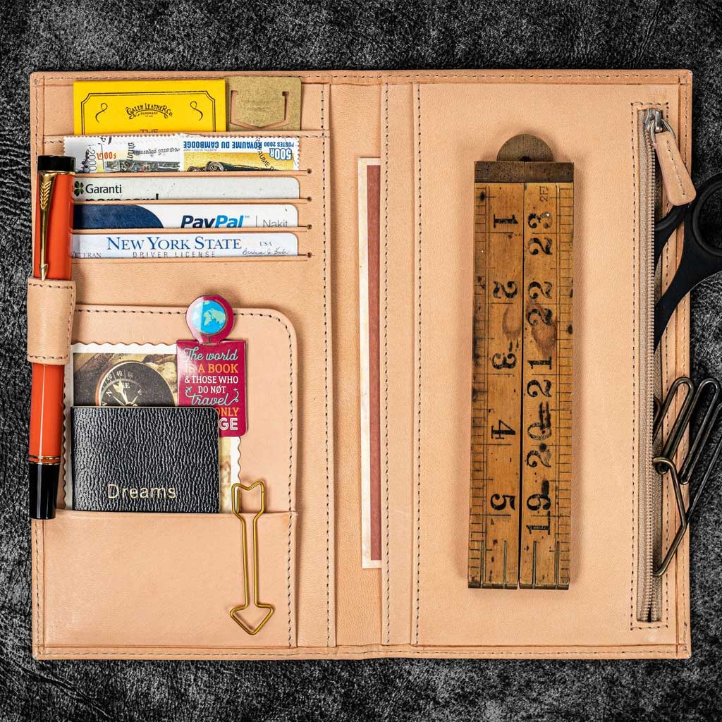 Open leather wallet with various cards and a ruler on a dark textured background