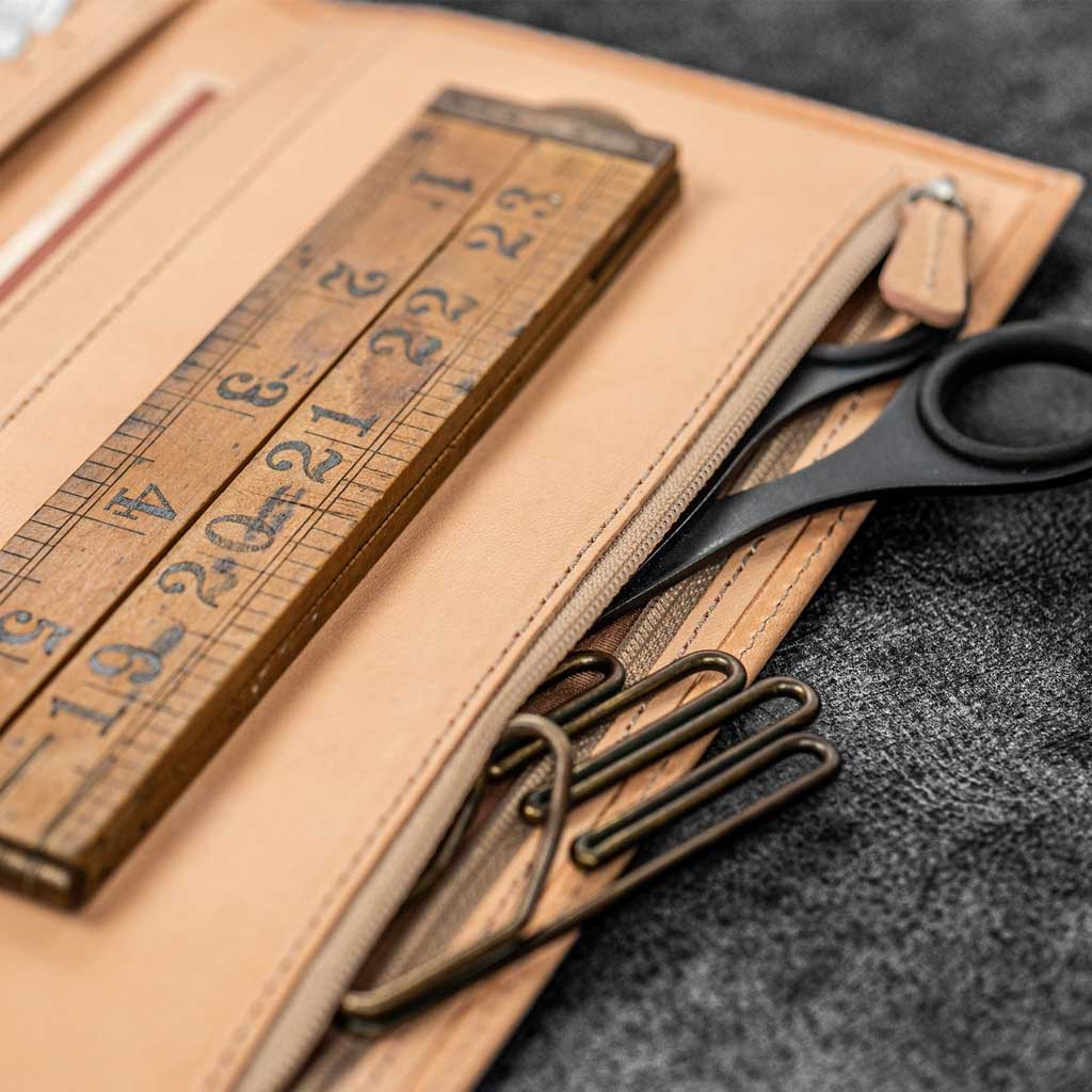 Natural undyed leather Traveler's Notebook wallet insert with clips and papers on wooden surface