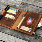 Brown leather wallet with various cards and a pen on a wooden surface