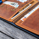 Brown leather wallet with various cards and a pen on a wooden surface