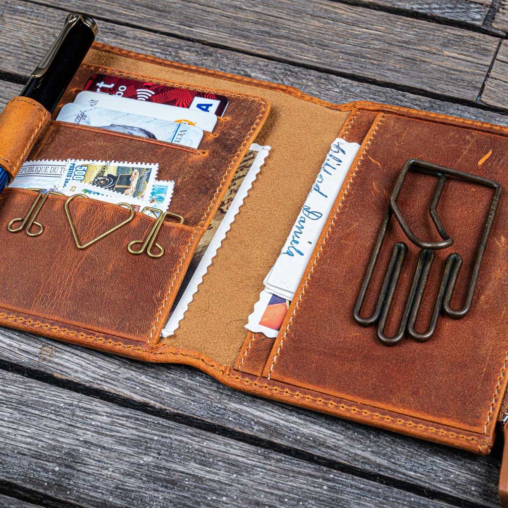 Brown leather wallet with various items on a wooden surface