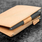Undyed natural leather wallet with pen on dark surface
