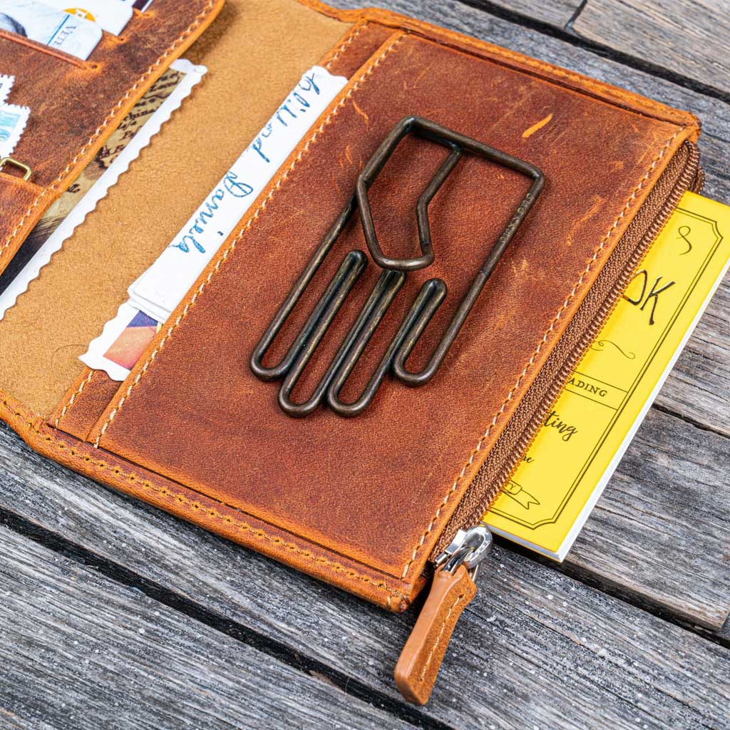 Brown leather wallet with a large paper clip on a wooden surface