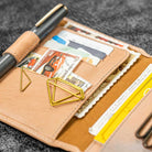 Open leather wallet with cards, notes, and a pen on a textured surface