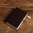 Brown Traveler's Notebook with undyed leather wallet insert on wooden surface
