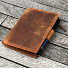 Brown leather wallet insert with a pen on a wooden surface