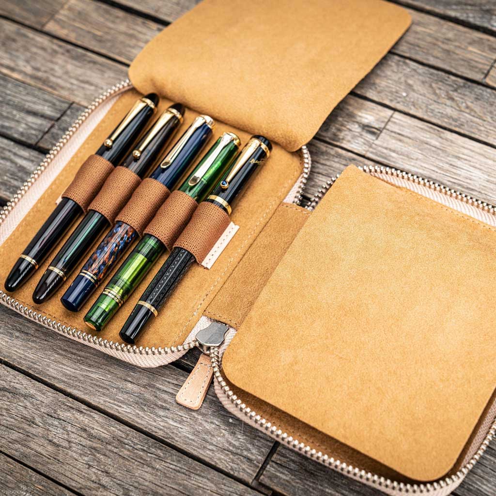Natural undyed leather pen case with pens and zipper on a wooden surface
