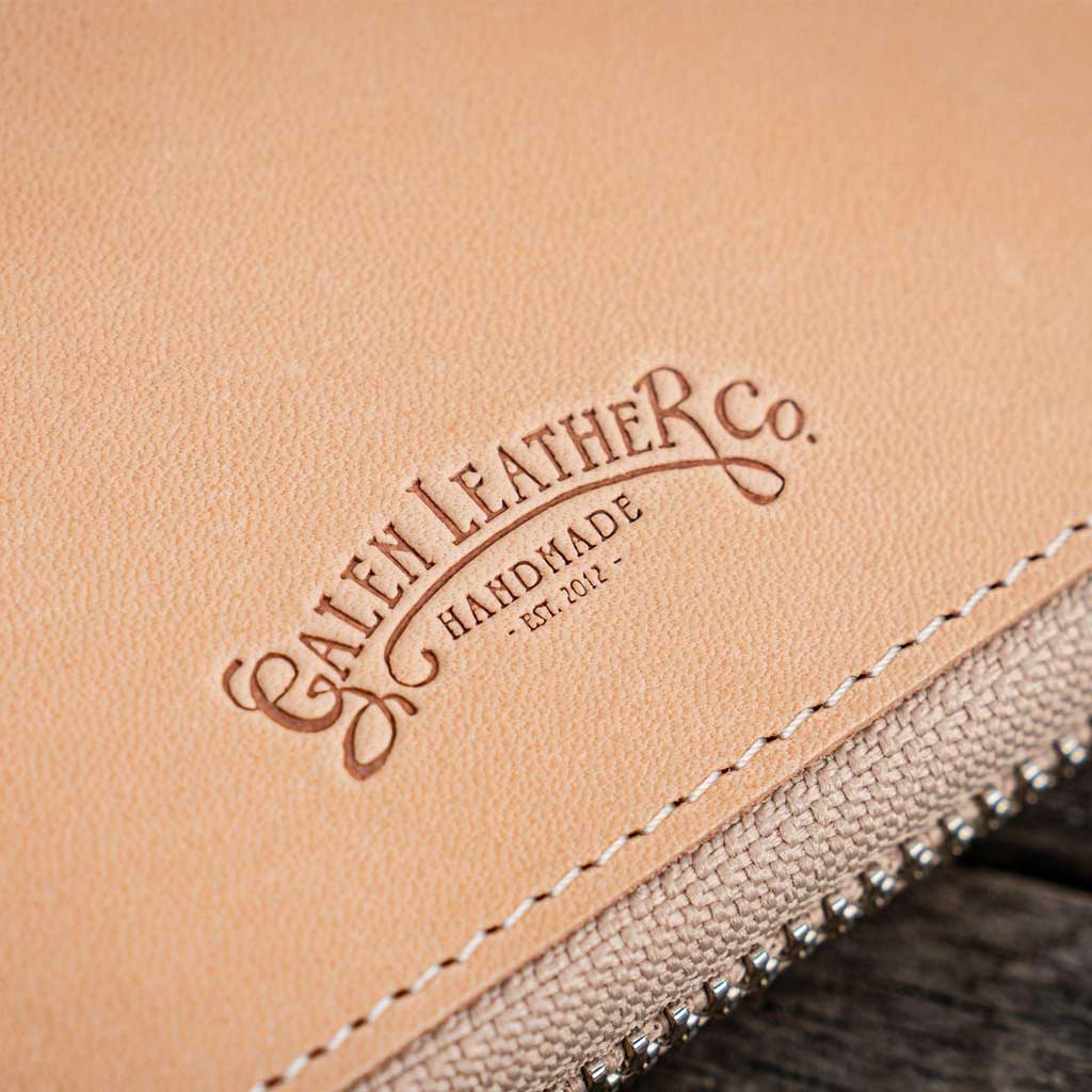Natural undyed leather pen case with Galen Leather branding and zipper on a wooden surface