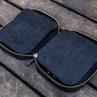 Black leather pen case with zipper on a wooden surface