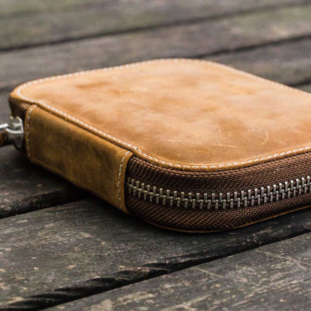 Brown leather pen case with zipper on a wooden surface