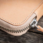 Natural undyed leather pen case with zipper on a wooden surface