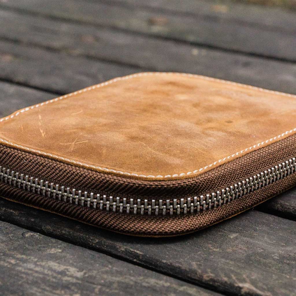 Brown leather pen case with zipper on a wooden surface