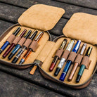 Brown leather pen case with ten pens and zipper on a wooden surface