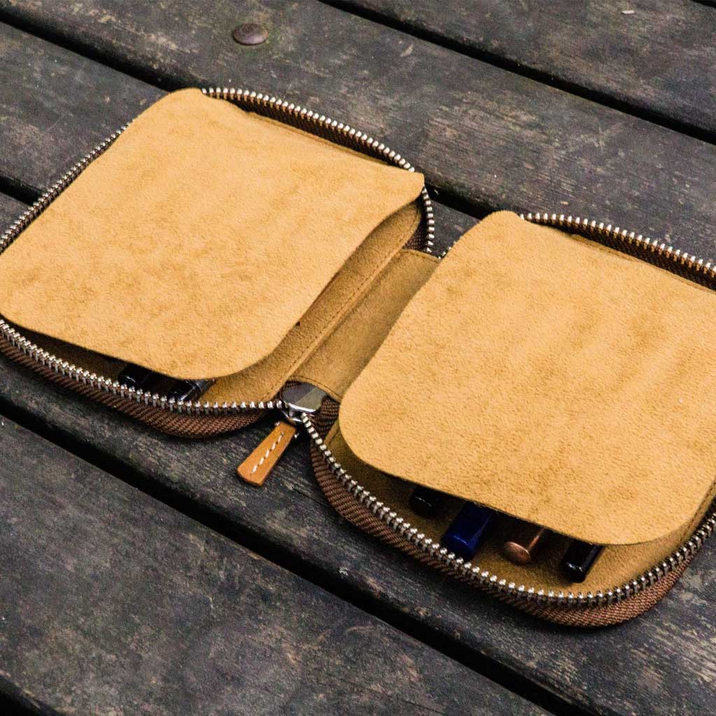 Brown leather pen case with zipper on a wooden surface