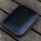 Black leather pen case with zipper on a wooden surface