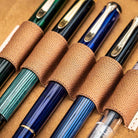 Set of fountain pens with brown fabric loops on a beige background