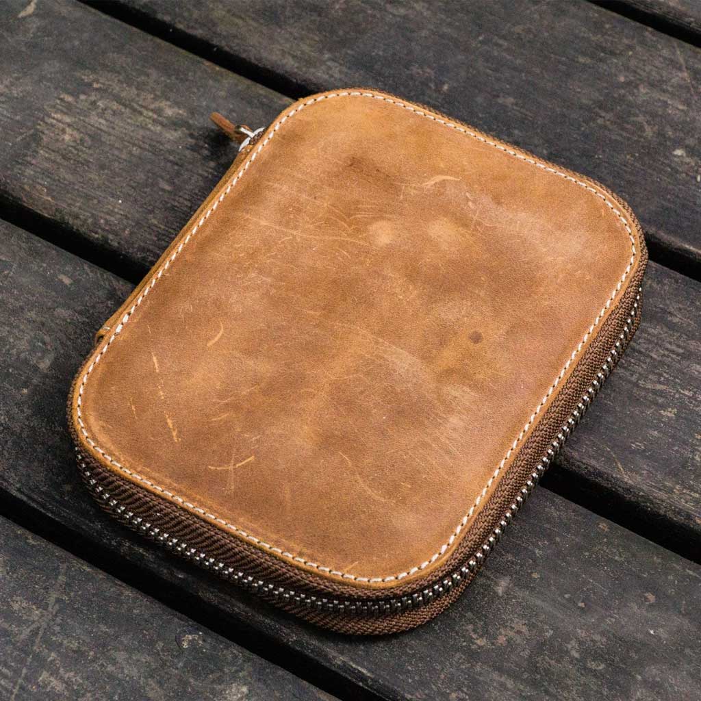 Brown leather pen case with zipper on a wooden surface
