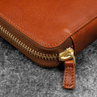 Brown leather zip pen case closed against dark background