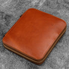 Brown leather zippered pen case on a gray textured background