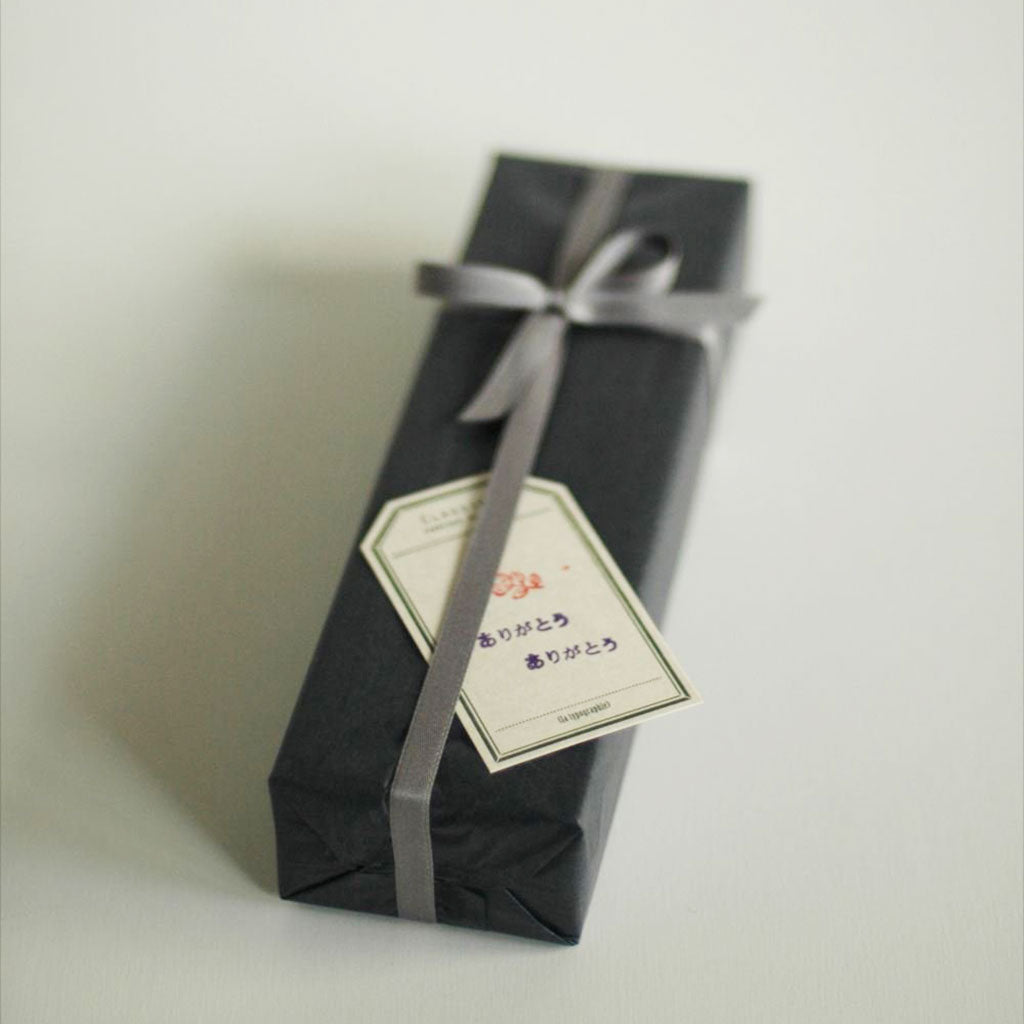A luggage tag-shaped label tucked under the ribbon of a wrapped present.