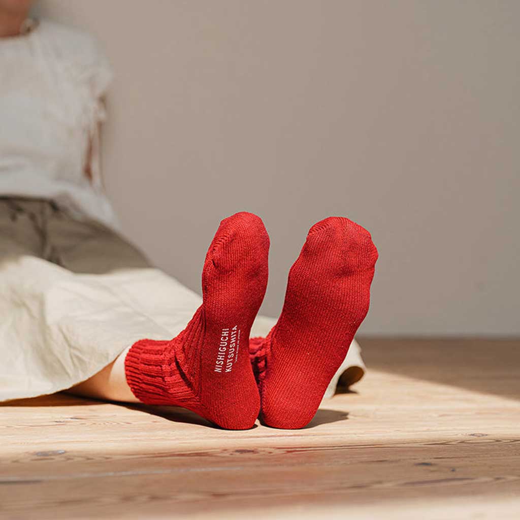 Red socks with a brand name on a wooden floor