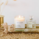 Candle labeled 'Love Potion' on a decorative tray with flowers and a perfume bottle.